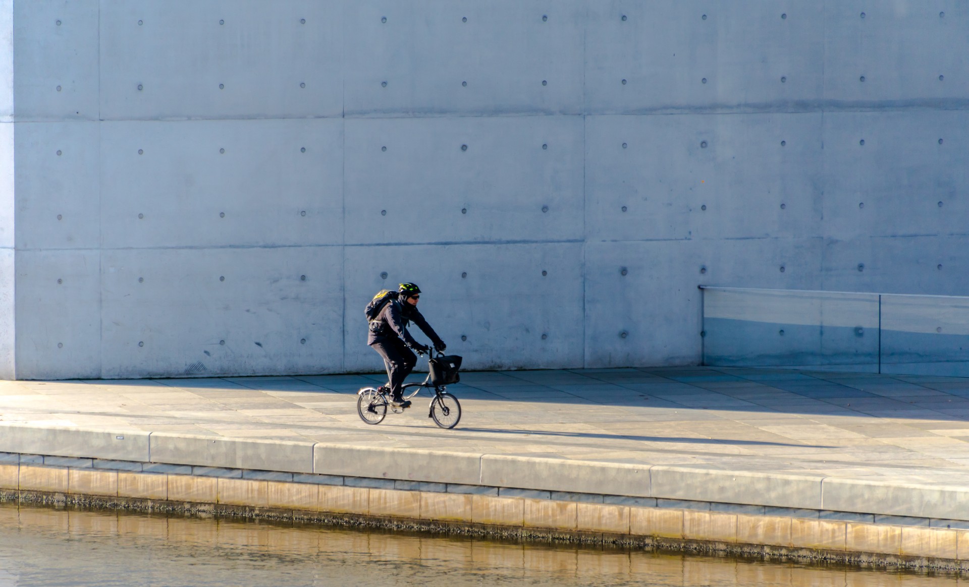 Mature Man Riding Bicycle On Street By River